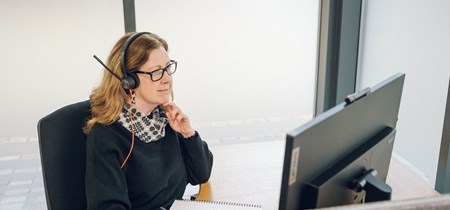 Woman working in office with headset and computer screen 
