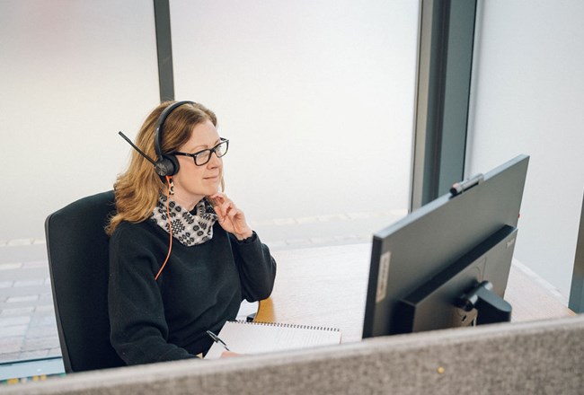 Woman working in office with headset and computer screen