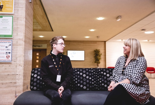 2 people having a discussion whilst sat on a sofa