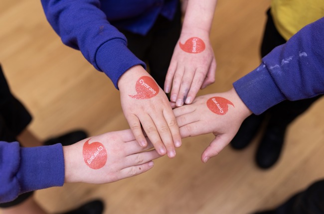 Image of children holding hands with iaith gwaith logo
