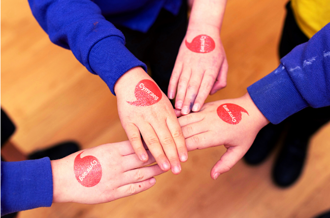 Iaith Gwaith logo on children's hands