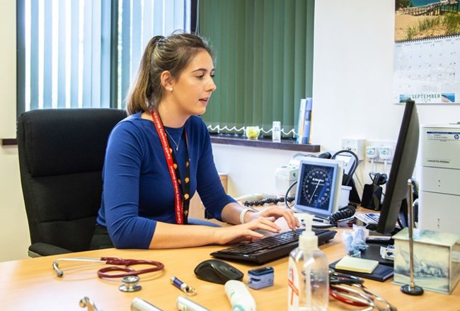 Doctor working on computer by desk